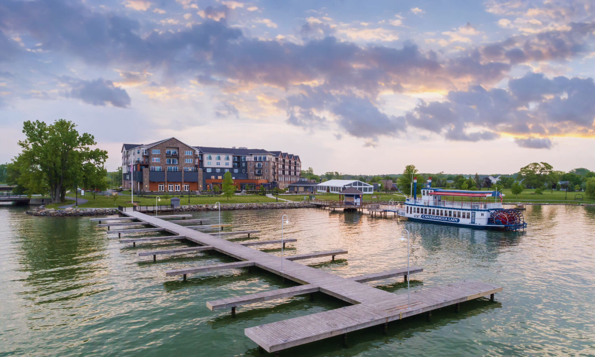 Lakeside exterior of Hotel Canandaigua in New York, featuring dock access, shoreline views, and a modern resort setting by the marina