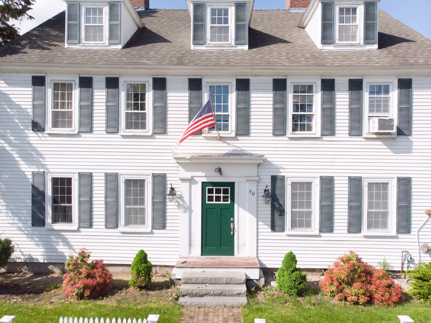 Historic inn exterior in Wolfeboro, New Hampshire, with traditional white siding, green front door, and timeless New England character
