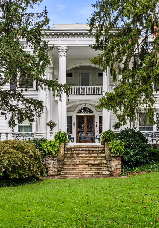 Historic inn entrance in Asheville, North Carolina, with neoclassical columns, landscaped grounds, and a stately elevated porch